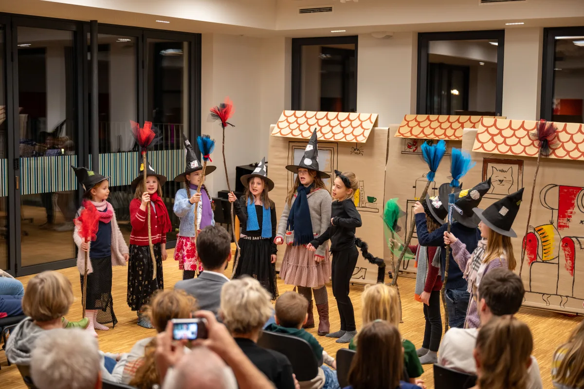 Kinder spielen gemeinsam eine Theaterszene vor Publikum